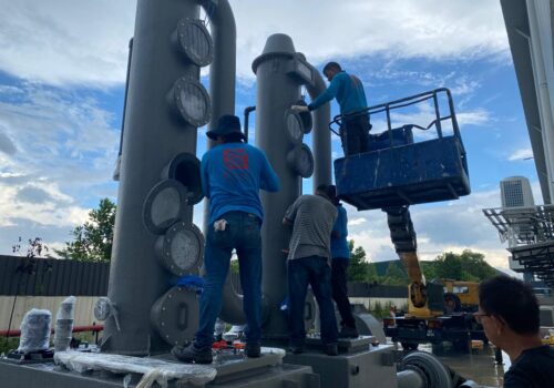 Technicians installing large Coriolis flow meters for precise measurement of liquids and gases